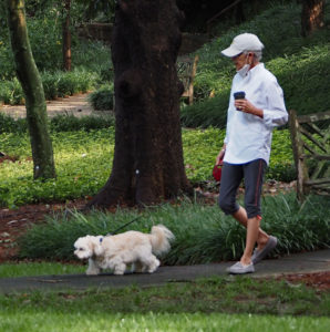Senior woman walking her dog on a trail outside her senior living community