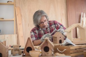 senior man creating a birdhouse from wood