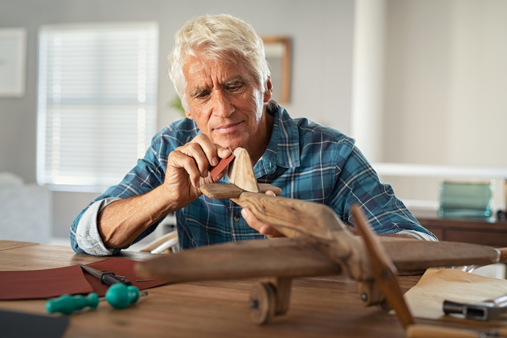 a senior man expresses his creativity making wood sculptures