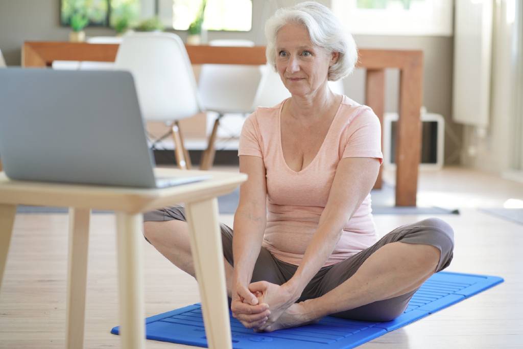 Senior woman practicing yoga virtually from her senior apartment