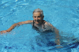 a senior woman swims in an indoor pool
