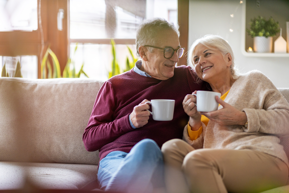 two seniors sit together and enjoy coffee in their senior apartment