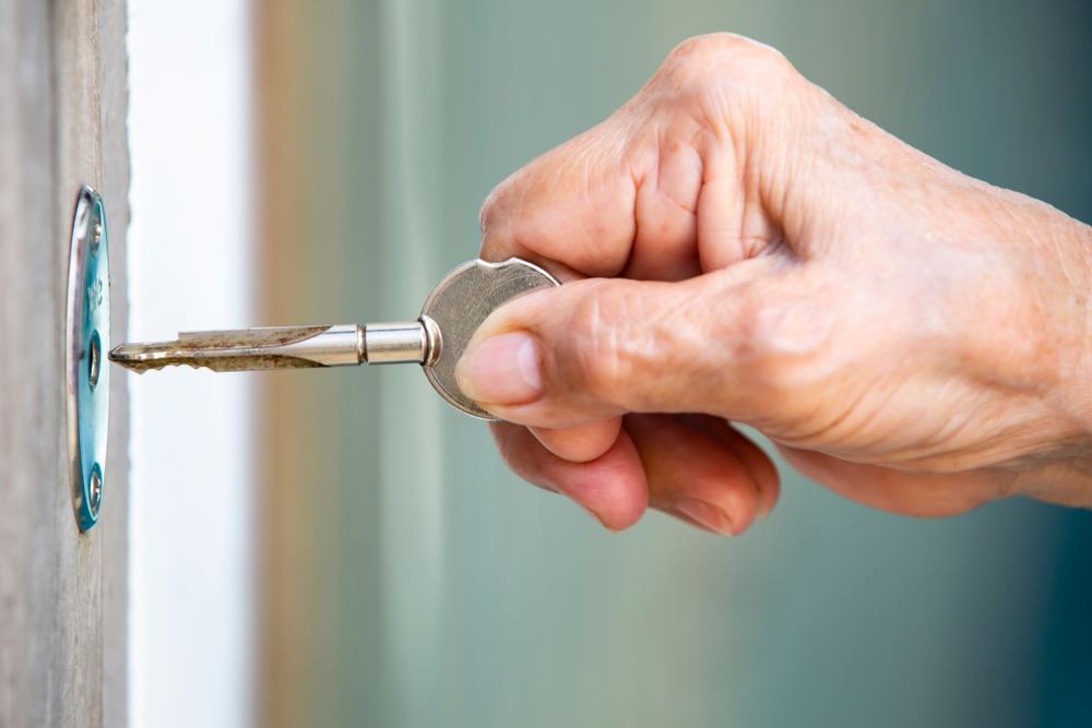 senior opening a door to their home with a key