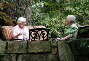 two elderly women drink coffee outside their retirement community