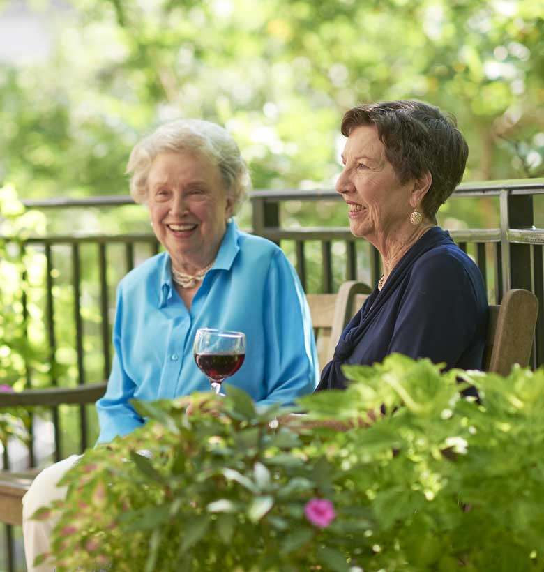 Senior women drinking and talking on bench at Canterbury Court